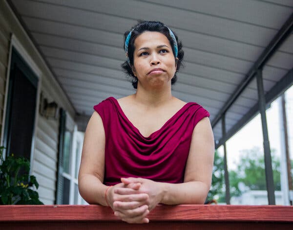A portrait of Jennifer Le wearing a red top as she leans over a bannister on her porch.